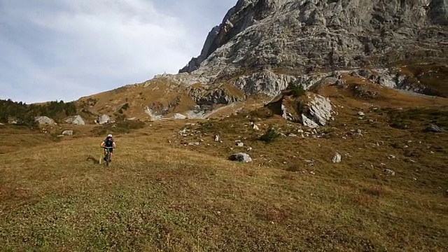 山地自行车手穿过山地草地视频素材