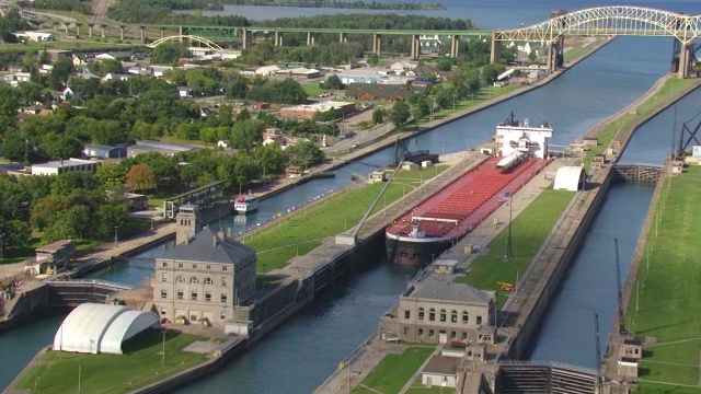 Soo Locks中的WS AERIAL POV驳船，背景中有桥/ Sault Ste。玛丽，密歇根州，美国视频素材