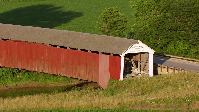 WS AERIAL POV Thorpe Ford Covered Bridge over river，农田和树木的背景/ Parke County, Rosedale, Indiana, United States视频素材