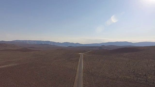 从空中俯瞰，骑自行车的人沿着空旷的道路穿过沙漠视频素材