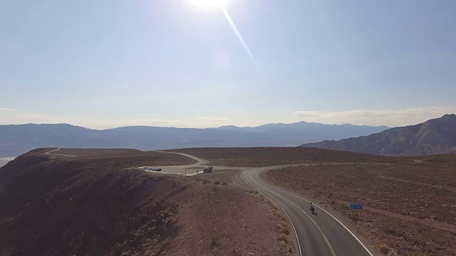 从空中俯瞰，骑自行车的人沿着空旷的道路穿过沙漠视频素材