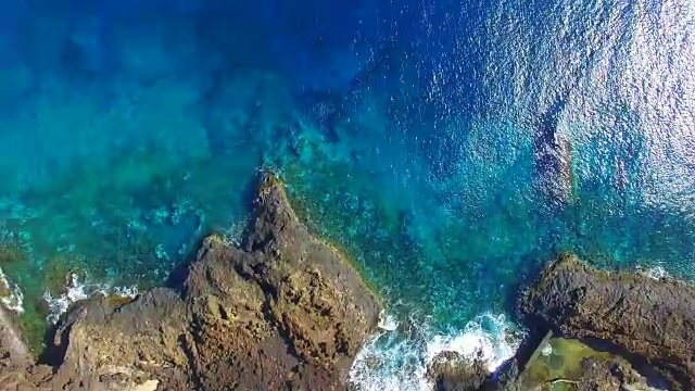 无人机在兰萨罗特火山岛上空拍摄的航拍镜头，海岸线上美丽的蓝色海水和绿色的池塘。4 k UHD。视频素材