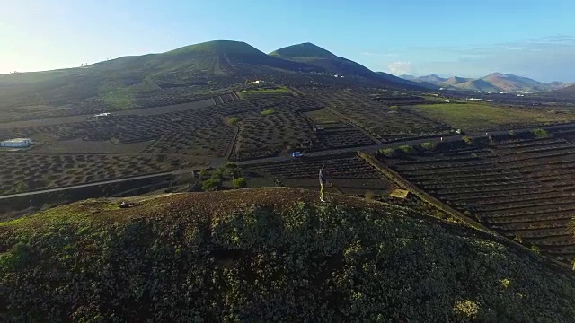 在兰萨罗特岛的火山山顶上，一个人在沉思并拍摄令人惊叹的火山景观。4 k UHD。视频素材