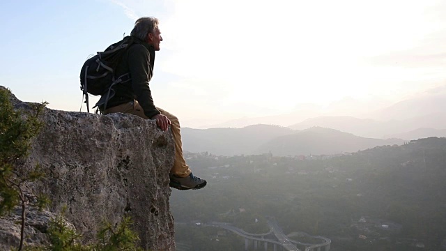 一名男性徒步旅行者从岩石上俯瞰山谷视频素材