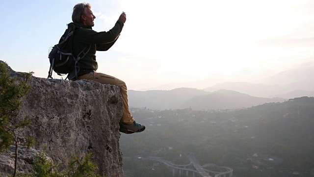 一名男性徒步旅行者从岩石上俯瞰山谷视频素材