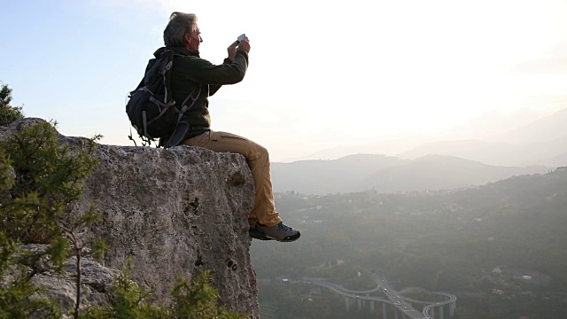 一名男性徒步旅行者从岩石上俯瞰山谷视频素材