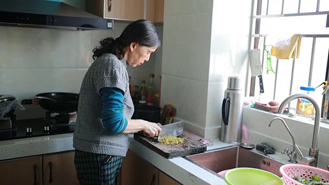 家庭烹饪:一位老年妇女在切蔬菜视频素材