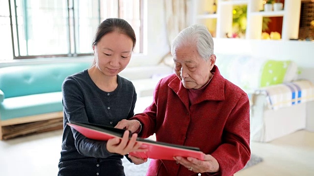 孙女和奶奶坐在一起看老照片。视频下载