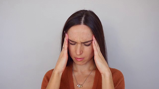 抑郁的女人患有偏头痛，她用手按住疼痛的太阳穴视频素材