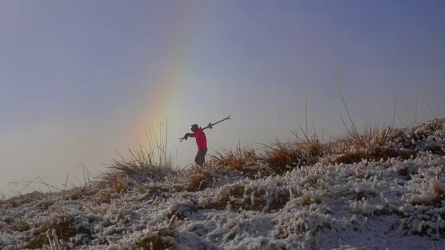 一个滑雪的人在雪山上走在彩虹里视频素材