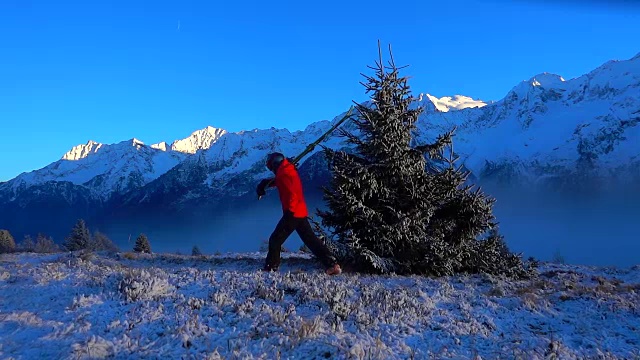 夕阳西下的雪山上，一个带着滑雪板的男人在行走视频素材