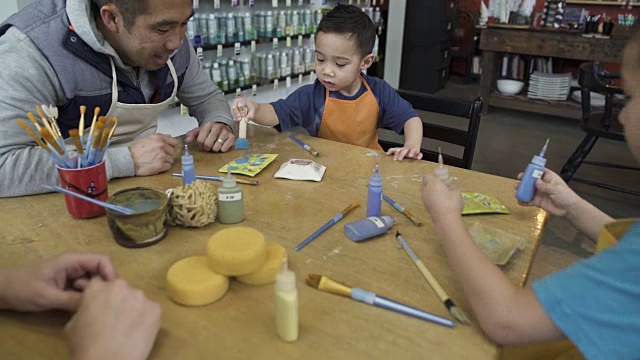 中宽镜头:两个小男孩在陶瓷工作室里挑选颜料视频素材