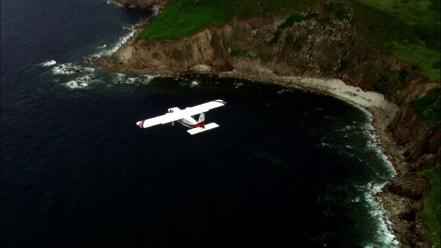 在英国康沃尔郡海岸、悬崖和海面上空飞过轻型飞机视频素材