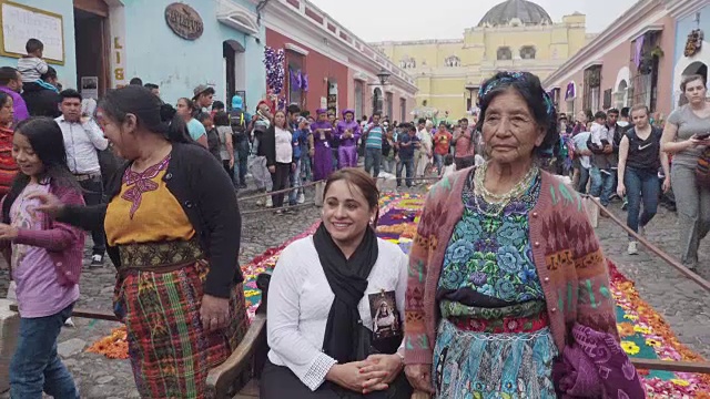 在危地马拉安提瓜举行的大斋节复活节庆祝活动中，妇女穿着玛雅服装在彩色地毯前摆姿势拍照视频素材