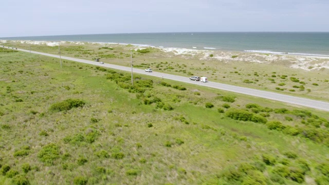 WS AERIAL POV汽车在路上行驶，背景是大海/美国北卡罗来纳州罗丹斯视频素材