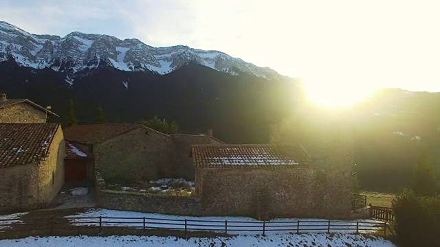 无人机在比利牛斯乡间山脉上空拍摄的航拍镜头，山顶上有美丽的石头小镇，日落时白雪皑皑的比利牛斯山脉的壮丽景色。4 k UHD。视频素材