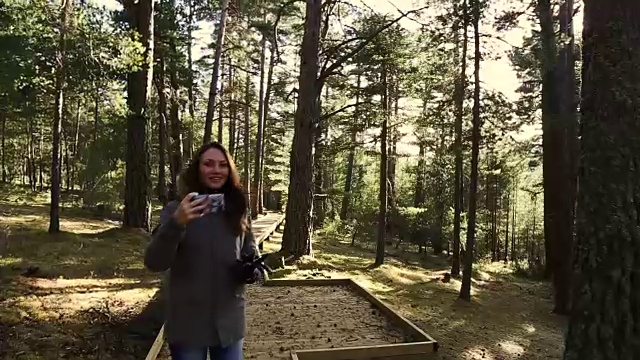 美丽的俄罗斯女孩步行和微笑在圣诞节假期在比利牛斯山脉的一个美丽的松树林与人行道和美丽的阳光。视频素材