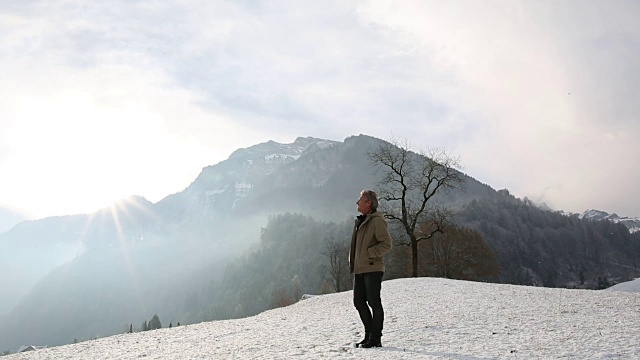 人类爬上了山上被雪覆盖的草地视频素材