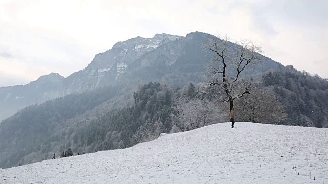 人类爬上了山上被雪覆盖的草地视频素材