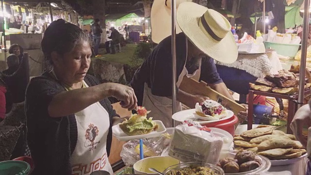 危地马拉安提瓜的街头食品市场。西班牙妇女烹饪鳄梨色拉酱和玉米饼卷视频素材