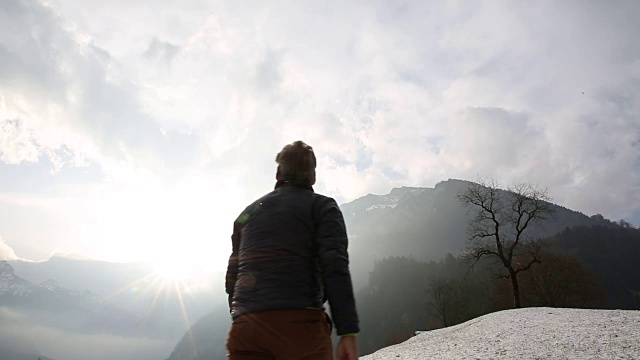 人类爬上了山上被雪覆盖的草地视频素材