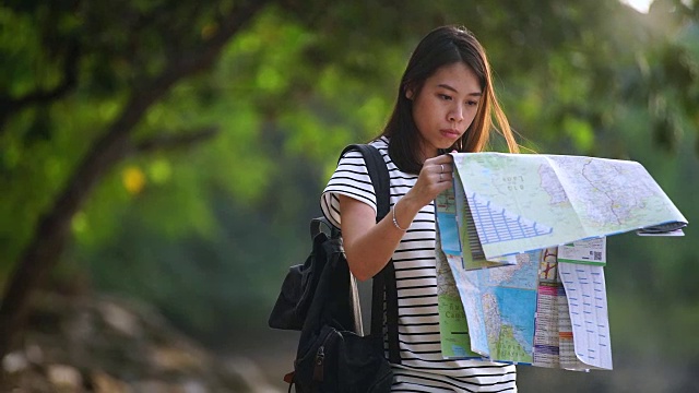 年轻女子背包欣赏海滩，看地图。视频素材