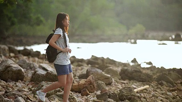 年轻女子背包欣赏海滩风景。视频素材