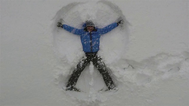 成年男子躺在刚下的雪中，做雪天使玩得很开心视频下载