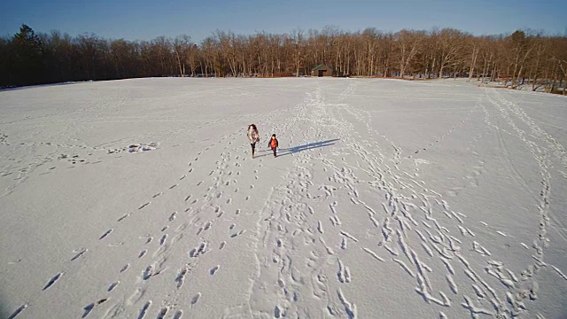 少女和小男孩在雪地上奔跑。慢动作航拍镜头。美国宾夕法尼亚州的波科诺斯视频下载