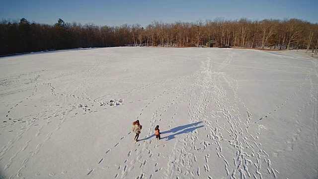 少女和小男孩在雪地上奔跑。慢动作航拍镜头。美国宾夕法尼亚州的波科诺斯视频素材