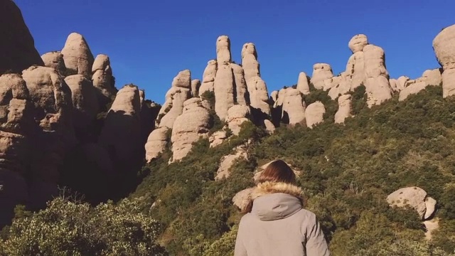 一个美丽的俄罗斯女孩在加泰罗尼亚地区旅行的慢镜头在蒙特塞拉特山脉与令人惊叹的风景在冬天的时间。视频素材