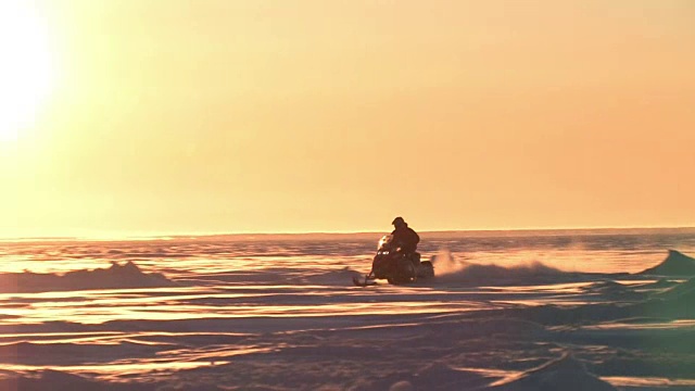 日落时分，白令海峡上，一名男子驾驶一辆雪地摩托视频素材