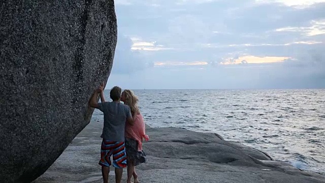 一对夫妇沿着海面上的石板和巨石走着视频素材