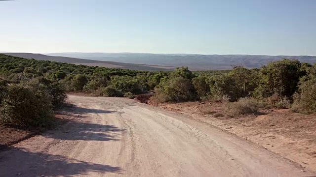 司机POV -缓慢驾驶/空的道路-部分13:土路/灌木丛/镜头眩光视频素材