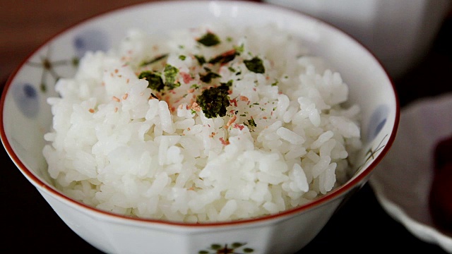 碗里撒调味料(茶水茶花米配日本杏子(日本传统食物))视频素材