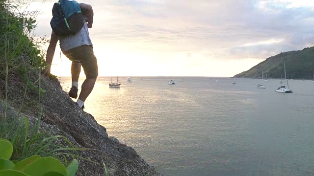 一名男性徒步旅行者穿过海面上的岩石板视频素材