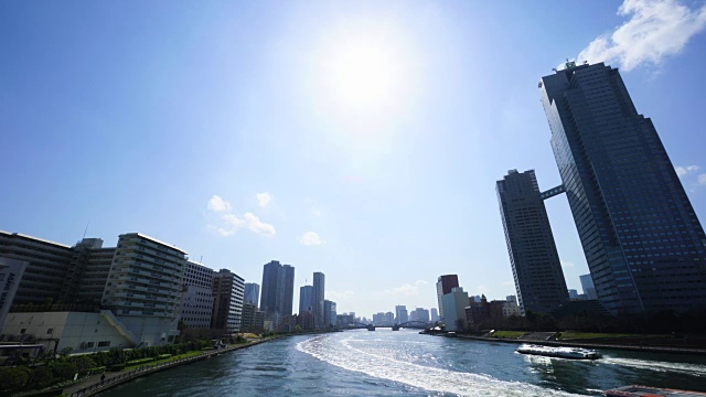 镜头捕捉住田河畔的城市景观从中央大西桥在中央，东京，日本。筑岛病房在左侧，筑地病房在右侧。游船在苏迈达河上行驶。在右岸可以看到圣路加花园塔视频素材