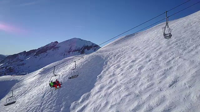 冬季假期，4k无人机拍摄两名滑雪者乘缆车上升视频素材