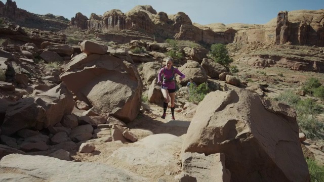 宽慢镜头低角度跟踪拍摄的女子trail跑在沙漠/摩押，犹他州，美国视频素材