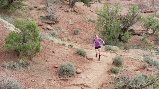 宽慢镜头高角度跟踪拍摄的女人trail跑在沙漠/费舍尔塔，美国犹他州视频素材