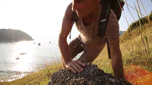 一名男性徒步旅行者在草坡上停下脚步，眺望大海视频素材