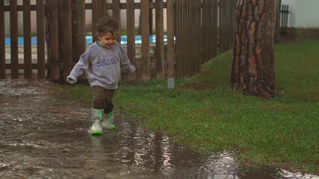 慢镜头，快乐的孩子在雨中嬉戏、跳跃、微笑视频素材