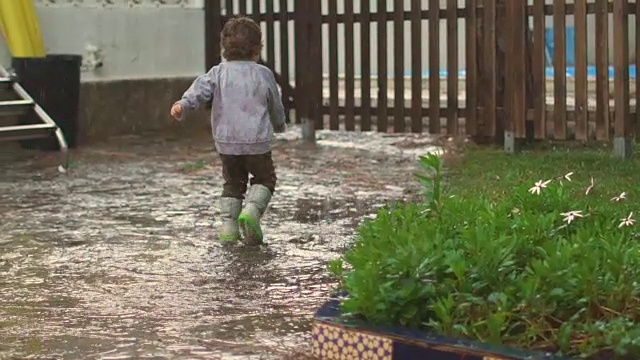 慢镜头，快乐的孩子在雨中嬉戏、跳跃、微笑视频素材