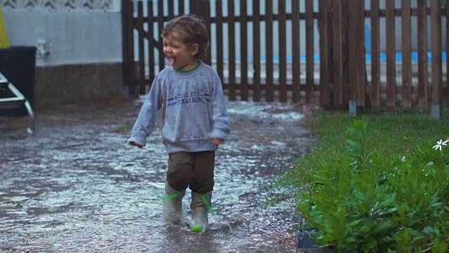 慢镜头，快乐的孩子在雨中嬉戏、跳跃、微笑视频素材