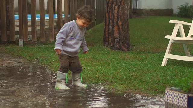 慢镜头，快乐的孩子在雨中嬉戏、跳跃、微笑视频素材