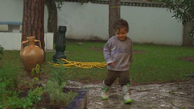 慢镜头，快乐的孩子在雨中嬉戏、跳跃、微笑视频素材