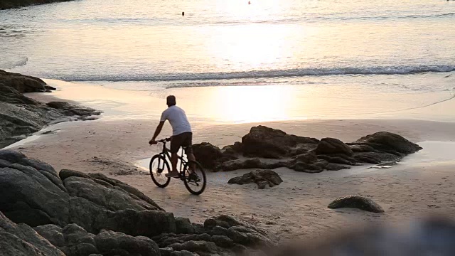 男子沿着海滩骑自行车，潮滩，日出视频素材