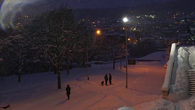 人们在公园里遛狗，在历史悠久的小镇Veliko Tarnovo，晚上被厚厚的积雪覆盖视频素材