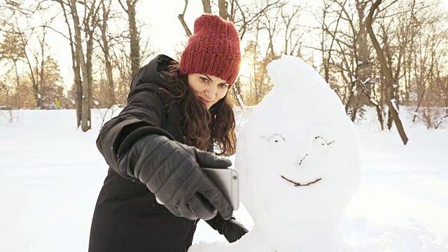 一个女人在和雪人自拍。视频素材