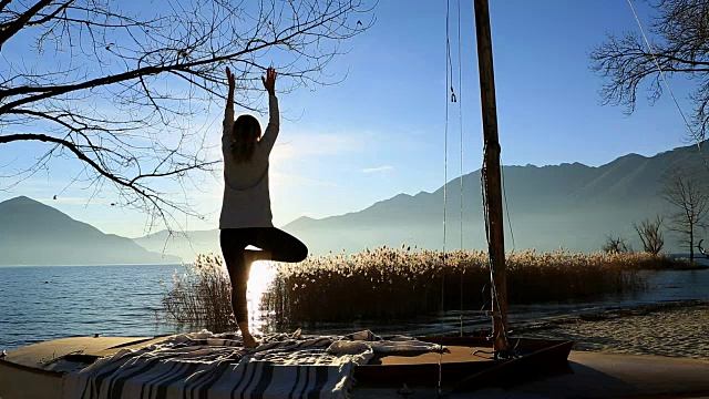 日落时分，年轻女子在湖边做瑜伽视频素材